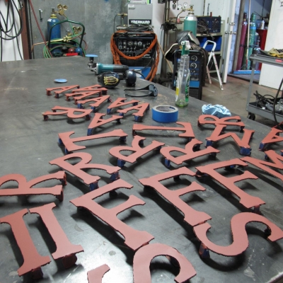Hand Cut Cor-Ten Letters about to be welded to the Sign 
